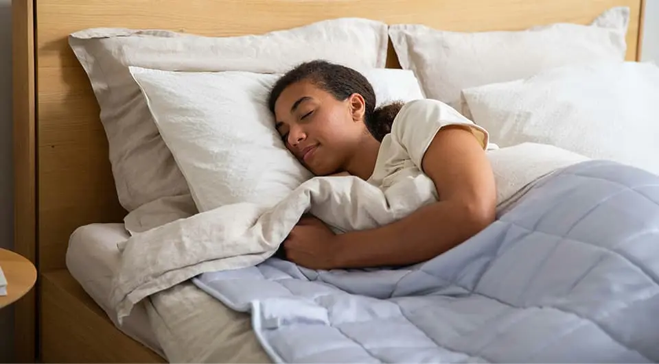 A woman sleeping peacefully and comfortably on a supportive mattress with light-coloured bedding in a bright bedroom.